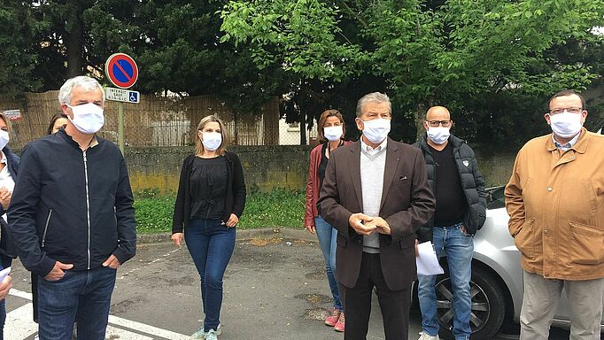 Sur la photo, le maire d'Uzès porte un masque. Il est entouré d'autres élus avec un masque.