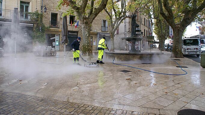 Les agents d'entretien nettoient la place Albert 1er d'Uzès avec des jets d'eau puissants.