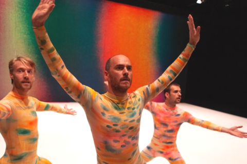 Trois hommes colorés effectuant une danse sur scène